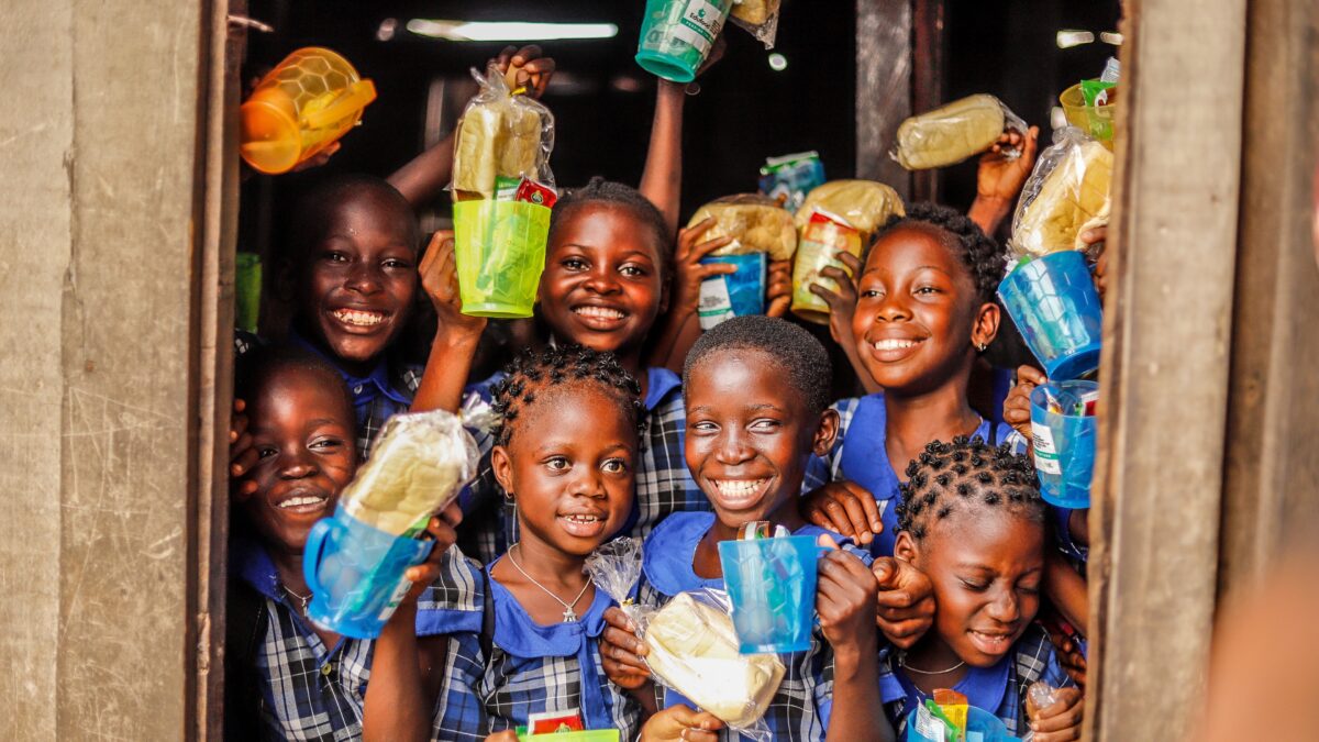 Un grupo de niños sonriendo con comida en las manos.